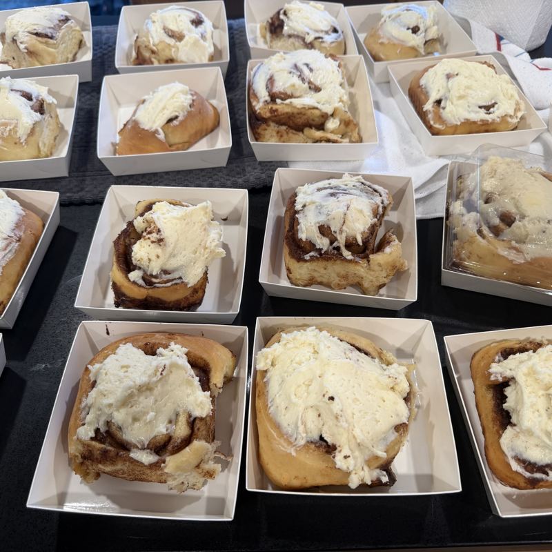 Trays of iced sourdough cinnamon rolls in paper boats